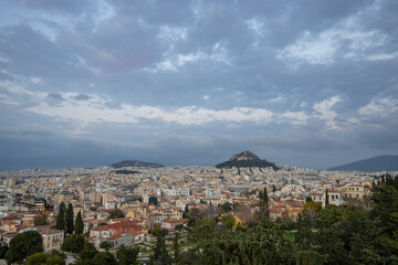 Naklejka premium View of the city of Athens November. Evening landscape, blue sky with clouds, soft light. Picturesque view from the hill to the old town.