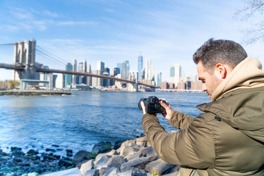 IMAGE OF A MAN FILMING THE SKYLINE OF NEW YORK CITY. TRAVEL AND SUNNY DAY CONCEPT.