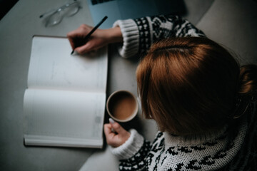 woman drinking coffee and taking notes in her diary