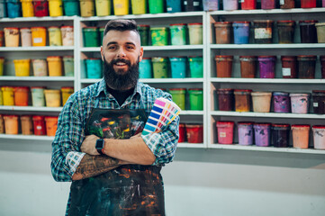 Male worker posing while mixing colors for screen printing in a workshop