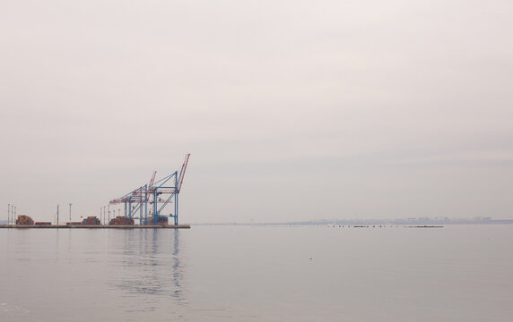 Odessa, Ukraine - 04 19 21: Containers in cranes in port docks. Gray foggy gloomy minimalistic photo with free empty copy space for text