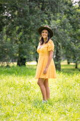 Naklejka na ściany i meble Portrait of Hispanic woman from Mexico, wearing a yellow dress and hat, with trees in the background