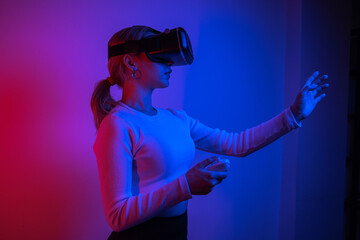 Woman wearing VR glasses and spending time controlling with joystick, studio photo with colorful glow