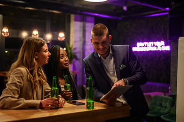 Cheerful colleagues drinking beer in the bar together after work