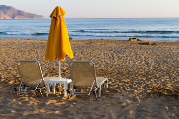 Beach sun beds and shade unbrella at sandy beach, Crete, Greece