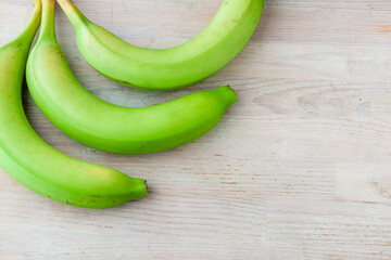 Three green bananas on a wooden background Healthy eating, fresh banana fruit, ripe banana, Bunch of bananas. Copy space