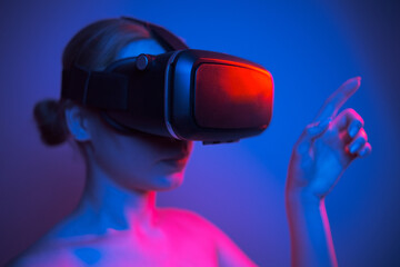woman in vr glasses stretching her finger to touch something in virtual world