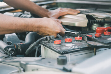 Automobile mechanic repairman hands repairing a car engine automotive workshop with a wrench.