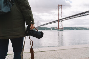 Woman photographer holding her camera on the 25 April bridge in Lisbon