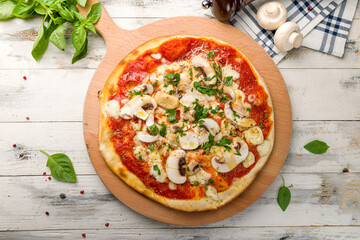 pizza with mushrooms, cheese and tomato sauce on the board top view on white wooden table