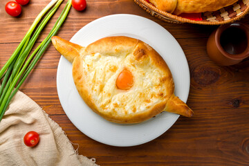 ajara Khachapuri with cheese, egg and butter, georgian kitchen on wooden table top view