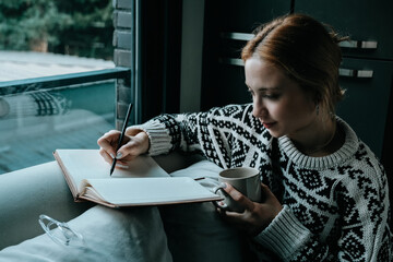 woman drinking coffee and taking notes in her diary