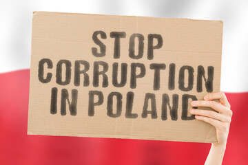 The phrase " Stop Corruption in Poland " on a banner in men's hand with blurred Polish flag on the background. Forbidden. Prevent. Wealth. Offence. Corruptness. Economy. Corruptible. Political