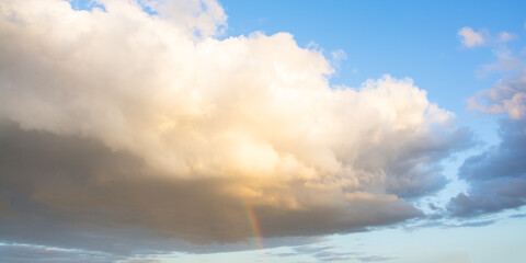 Ciel. Gros nuage avec une éclaircie après la pluie en soirée et un petit arc en ciel.