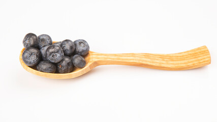 fresh blueberries lie in a wooden spoon on a white background. vitamin organic food