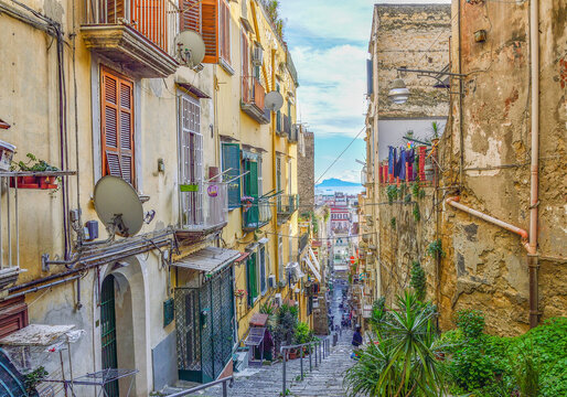 Typical street of Naples old town: narrow, steep, delapidated, picturesque, with jalousies on windows, flower pots and drying laundry