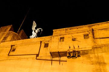 Brick wall, old clock with bells and the angel statue on the top  of the Castle of the Holy Angel...