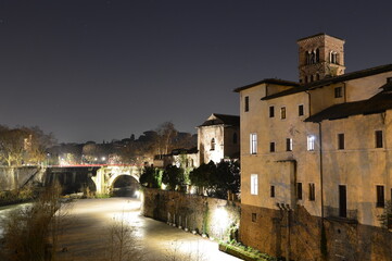 The night view of Basilica of St. Bartholomew on the Tiber Island and Pons Aemilius (Italian: Ponte Emilio), today called Ponte Rotto, the oldest Roman stone bridge in Rome, Italy.
