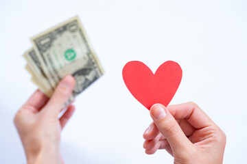 a hand with a heart and an out-of-focus hand with money