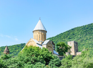 Fototapeta na wymiar Ananuri church and fortress in Georgia. Blue sky, grenn mountains, sunlight and shadows on the ancient stones