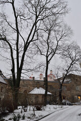Vilnius old town yard and house road in a cloudy winter evening. brick fence, naked trees, old churches and bell towers on the horizon