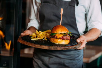 Closeup of the hands of a waiter holding a cheeseburger