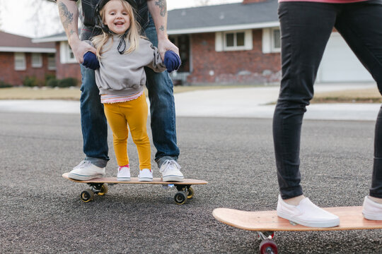 A Smiling Girl Stands on a Skateboard Surrounded by Family