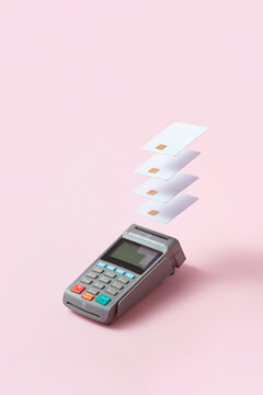 Terminal with credit cards on pink background