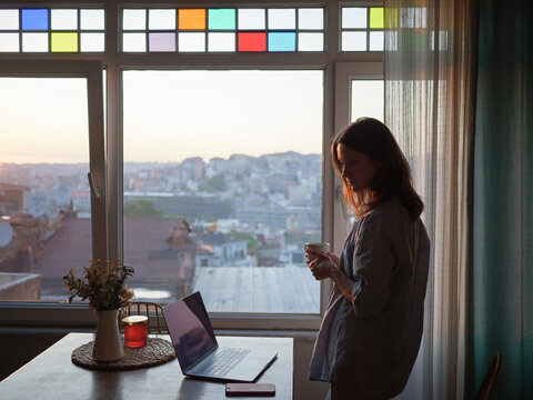 Woman looking to the window with laptop on the table