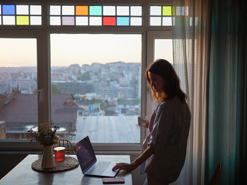Woman looking to the window with laptop on the table