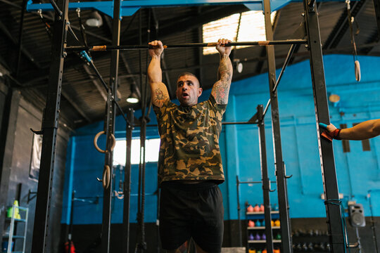 Tattooed sportsman doing pull ups on bar