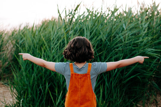 Girl in gold and stipes pointing two directions. Close.