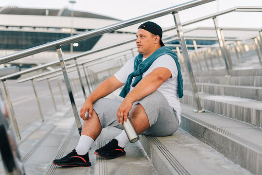 White man in a sportswear sitting on the steps