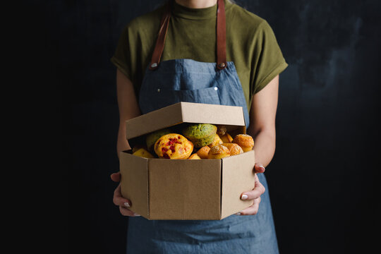 Woman holding a box of muffins.