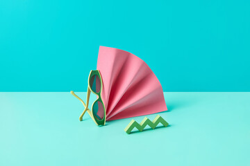 Green sunglasses near pink hand fan