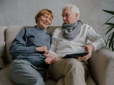 Senior couple playing on tablet laughing