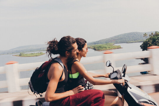 Couple riding on scooter through the bridge in Asia