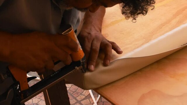 hans of an upholsterer stapling a fabric after having measured under natural light