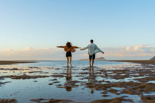 Young couple enjoying sunset at empty beach - Powered by Adobe
