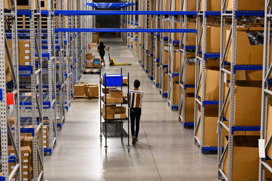 Workers Moving merchandise with cart on warehouse floor 
