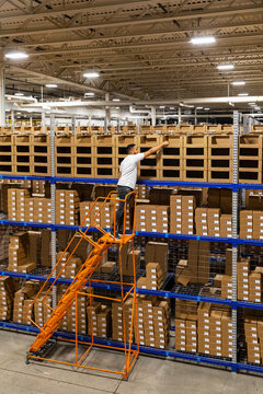 Man Picking order from boxes at E-Commerce Warehouse 