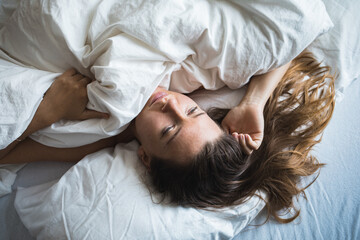 Woman in bed slowly waking up