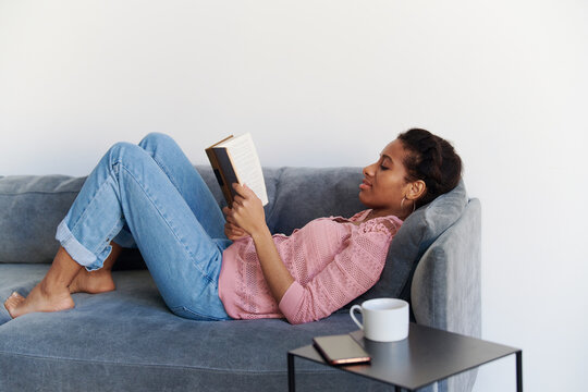 Portrait of a relaxed girl reading a book at sofa