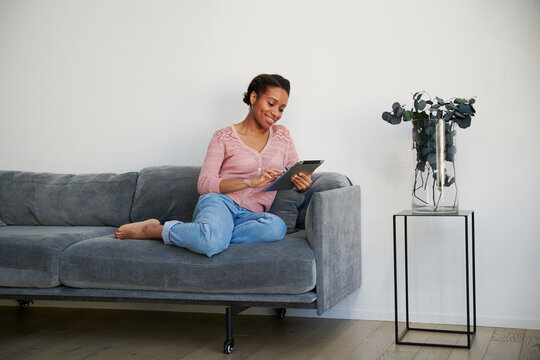Woman smiling while holding a tablet computer in a living room