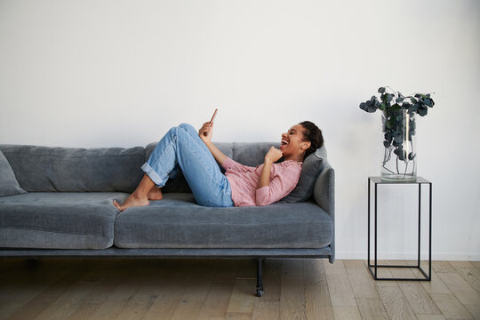 Woman lies on the sofa with the phone in her hands