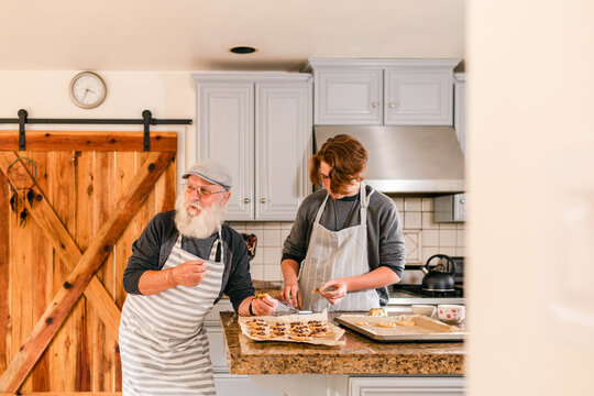 Teenager and grandfather baking cookies in kitchen
