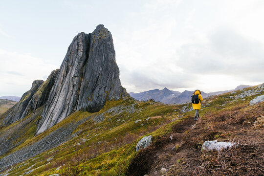 Anonymous backpacker climbing up hill