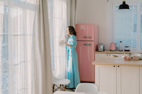 Woman In A Pretty Kitchen Looking Outside