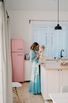 Mother talking to her daughter in the pink kitchen