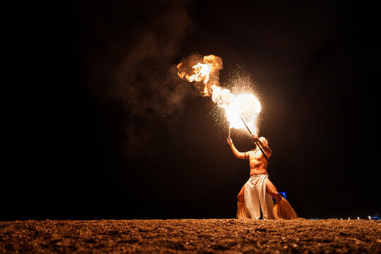 Tribal performer blowing on bright fire